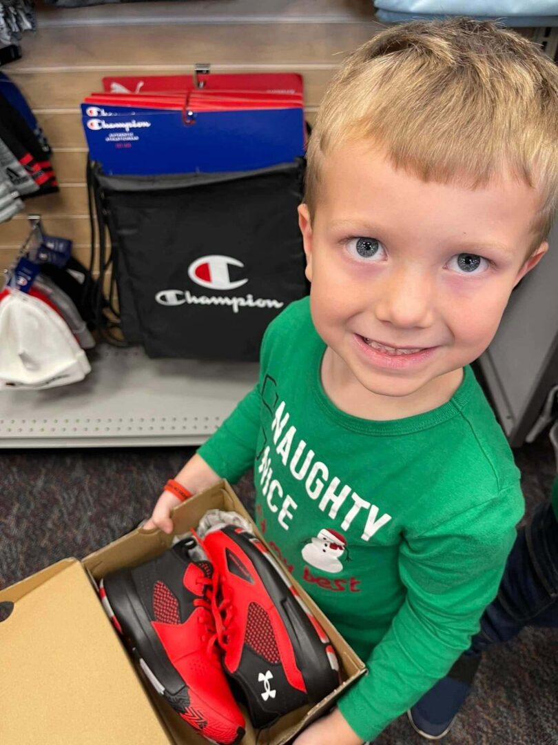 A young boy holding onto a pair of shoes