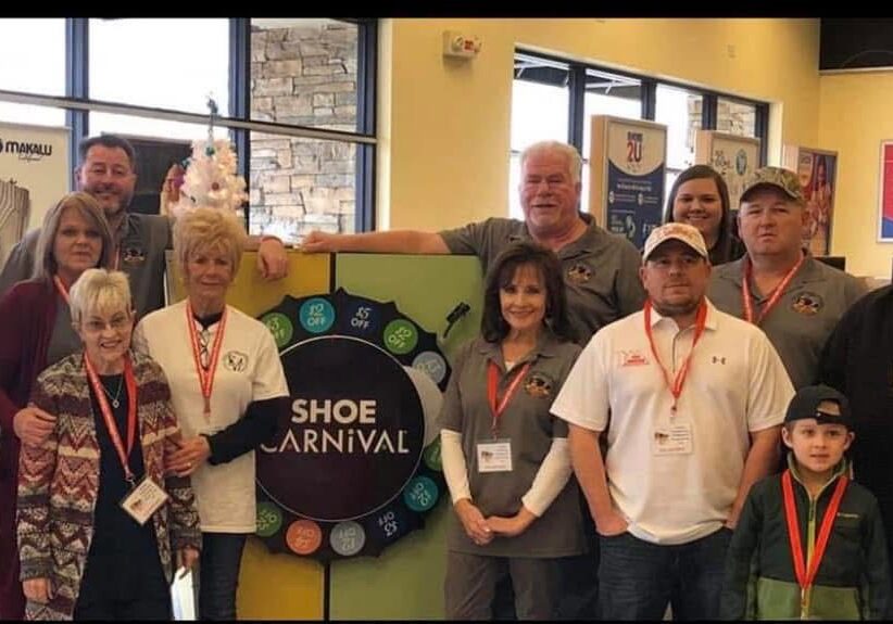 A group of people standing in front of a sign.